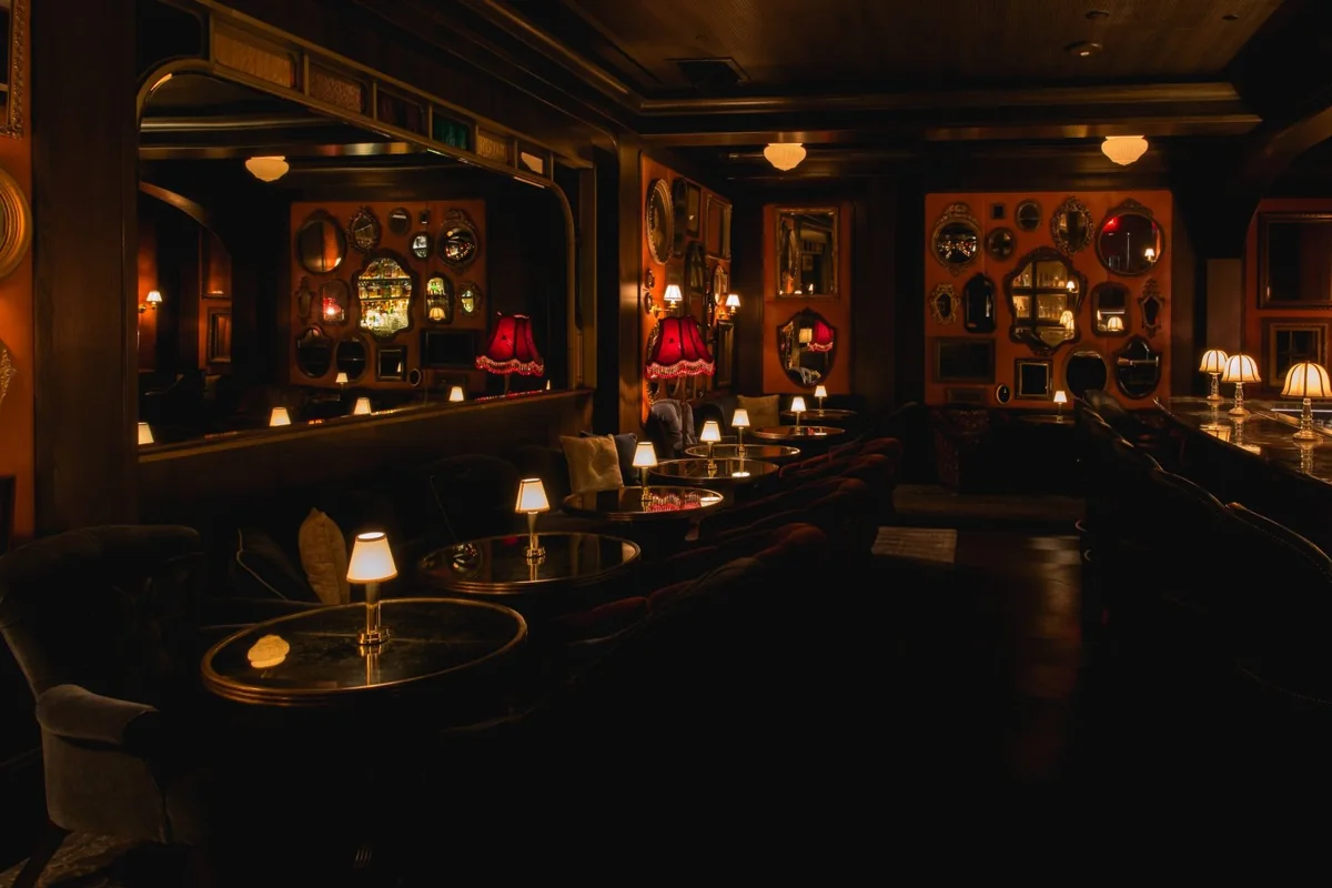The Parlor at Bavette's Las Vegas: round tables with small shaded lamps, red fringed lampshades and walls hung with gilt mirrors.